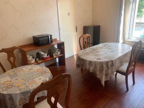a dining room with two tables and chairs and a television at Le Pontet in Miramont-de-Guyenne
