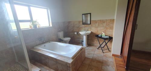 a bathroom with a tub and a toilet and a sink at Berlouri Guest House in Hekpoort
