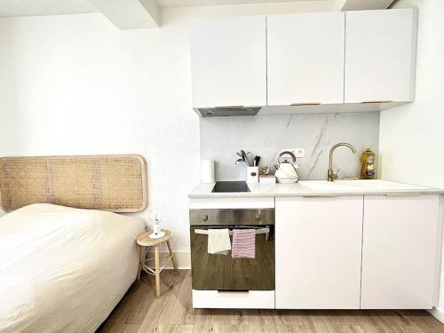 eine weiße Küche mit einem Waschbecken und einem Bett in der Unterkunft Le Nacre 24 - Bourg-de-Péage in Bourg-de-Péage