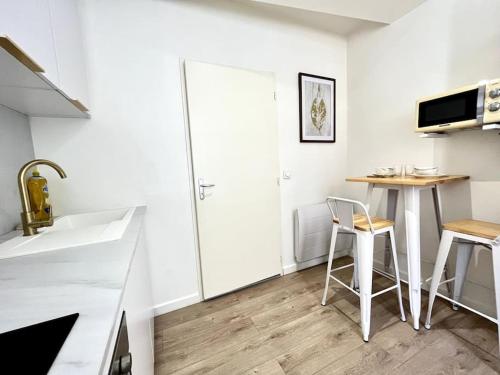 eine Küche mit einem Waschbecken und einem Tisch mit zwei Stühlen in der Unterkunft Le Nacre 24 - Bourg-de-Péage in Bourg-de-Péage