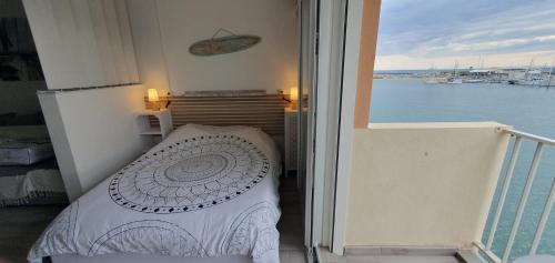 - un balcon avec un lit et une vue sur l'eau dans l'établissement Appartement avec balcon, vue Mer, Piscine, Parking, au Cap d'Agde