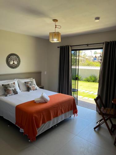 a bedroom with a bed and a large window at Pousada Vielas do Rosa - centrinho da praia do rosa in Praia do Rosa