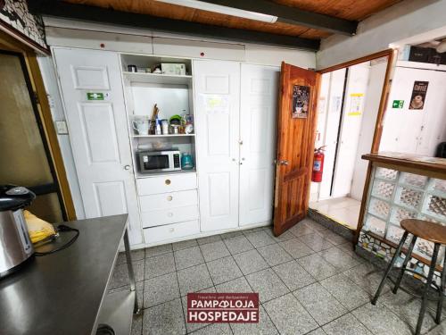 a kitchen with white cabinets and a microwave at Hostal Pampaloja Antof in Antofagasta