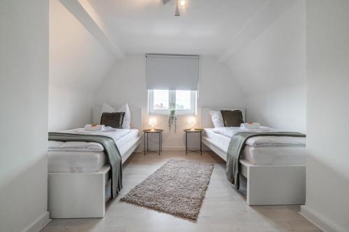 2 camas en una habitación blanca con alfombra en - NICE & CALM - Perfect for Families, Friends, Couples en Wesel