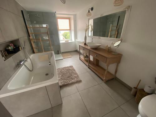 ein Badezimmer mit einer Badewanne, einem Waschbecken und einem Spiegel in der Unterkunft Au saut du Train in Remicourt