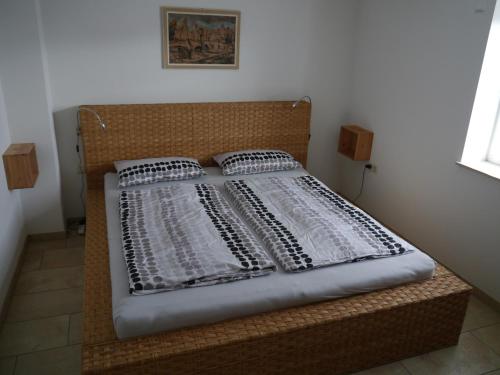a bed with a wooden headboard and two pillows at Ferienwohnung Dada in Oettingen in Bayern