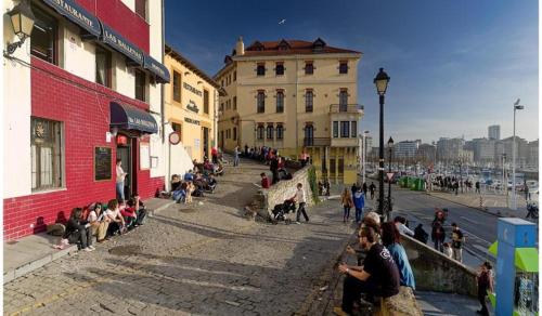 a group of people sitting on a sidewalk in a city at Friendly vistas mar apart 3H y garaje in Gijón