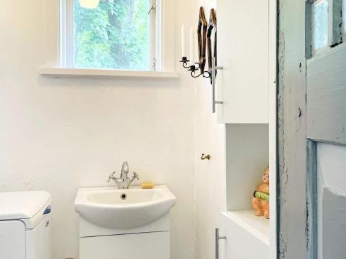 a white bathroom with a sink and a window at Holiday home MARIESTAD XI in Mariestad