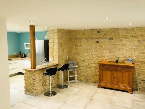 a kitchen with two bar stools and a stone wall at Gîte Damat in Asnelles