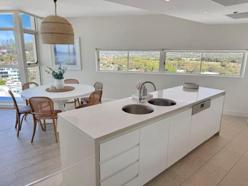 uma cozinha com um lavatório e uma mesa com cadeiras em Kirra Penthouse with Private Spa em Gold Coast