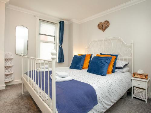 a bedroom with a white bed with blue and orange pillows at Captains Lockyer in Kingswear