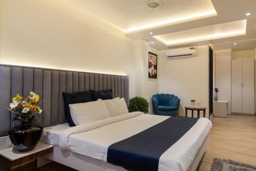 ein Schlafzimmer mit einem großen Bett und einem blauen Stuhl in der Unterkunft Hotel Meghdoot, Bhopal in Bhopal