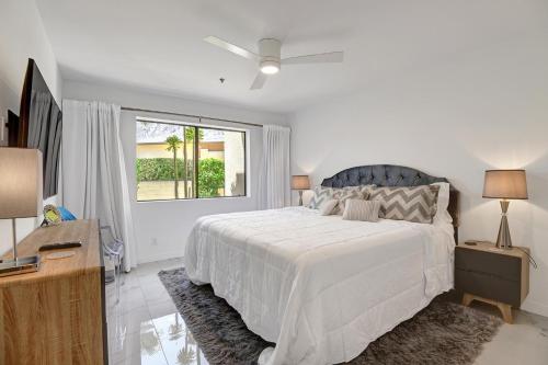 een witte slaapkamer met een groot bed en een raam bij Modern Plaza Villas Oasis in Palm Springs
