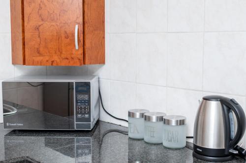 a kitchen counter with a microwave and cups on it at Tranquil cottage in Sandton