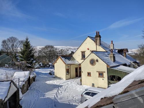 een huis in de sneeuw met een auto bij The Hayloft, Marsden in Huddersfield