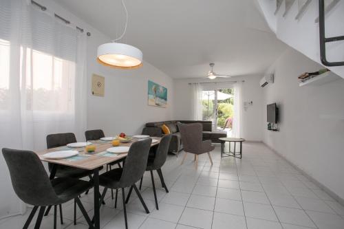 a dining room and living room with a table and chairs at Casa Del Sol Townhouse in Iris Village Paphos in Paphos City