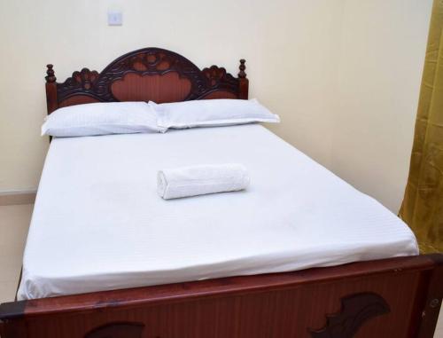 Bett mit einem Kopfteil aus Holz und einer weißen Matratze in der Unterkunft Marie's 1br near Sarovawoodlands in Nakuru