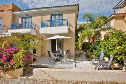 a house on the beach with a table and chairs at Casa Del Sol Townhouse in Iris Village Paphos in Paphos City