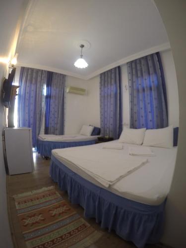 a bedroom with a large bed and blue curtains at Akkin Pansiyon in Kaş