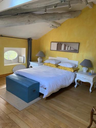 - une chambre avec un grand lit et un mur jaune dans l'établissement Le Clos Fanny chambre d’hôtes, à Saint-Jean-de-Bournay