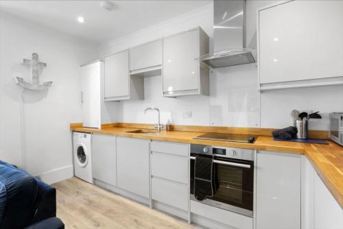 a kitchen with white cabinets and a sink at Ahoy There! in Hythe