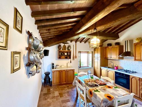 a kitchen with wooden ceilings and a table with chairs at Poggiosalto in Toscana in Pienza