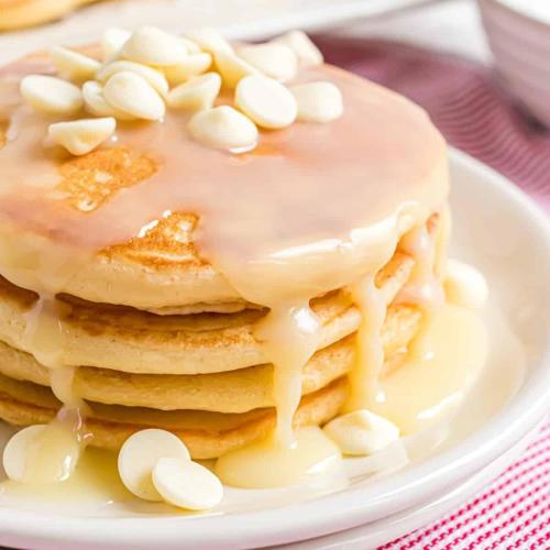 a stack of pancakes with icing and marshmallows on a plate at Eleni Rooms in Parikia