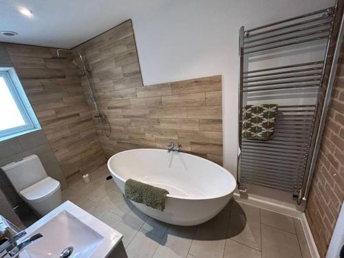 y baño con bañera, aseo y lavamanos. en 3 - Rabbit Warren, Bright décor home & private hot tub, en Norwich