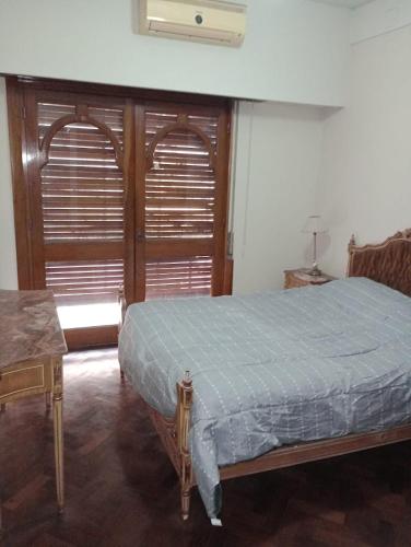 1 dormitorio con 1 cama y 2 puertas de madera en Cómo en casa en Rosario