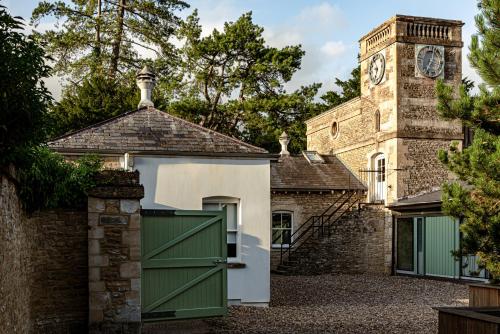 a brick building with a green garage door and a clock tower at Cowley Manor Experimental in Cheltenham