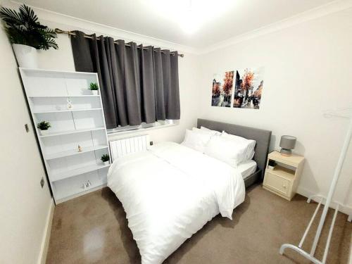 West Byfleetにある2 BEDROOM APT WITH 2 COMFORTABLE KING SIZE BEDs, FREE PRIVATE PARKING, EASY ACCESS TO LONDONのベッドルーム(白いベッド1台、窓付)