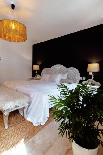a bedroom with a large white bed and two plants at Elviria beach Award-Winning Stay in Marbella