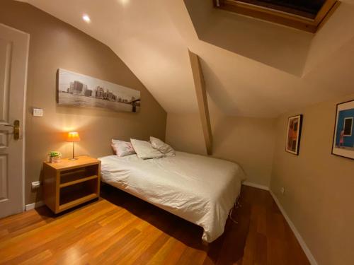ein Schlafzimmer mit einem Bett und einem Nachttisch mit einer Lampe in der Unterkunft CHAMBRE AU CENTRE VILLE TRES COSY in Nancy