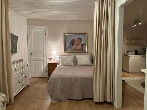 1 dormitorio con 1 cama con una pintura en la pared en Lilla gröna huset på gården, en Härnösand