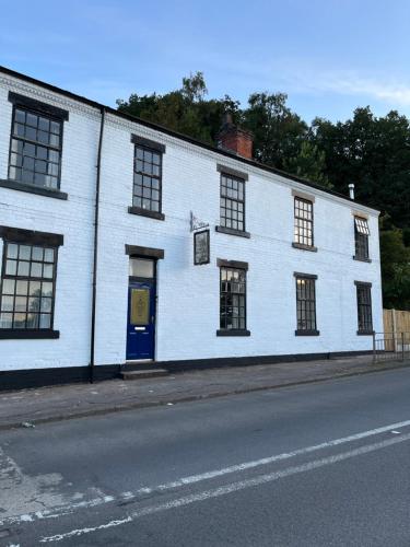 a white building with a blue door on a street at The Old Postie Bed & Breakfast in Annesley