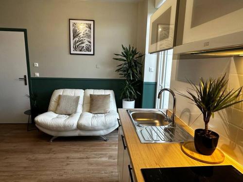 un salon avec un canapé blanc et une cuisine dans l'établissement L'Écrin Vert - rez de chaussé - idéalement situé - terrasse, à Boulogne-sur-Mer