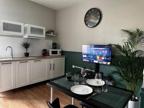 Il comprend une cuisine avec une table et une télévision murale. dans l'établissement L'Écrin Vert - rez de chaussé - idéalement situé - terrasse, à Boulogne-sur-Mer