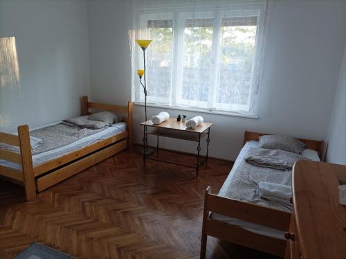twee bedden in een kamer met een tafel en een raam bij Róza Vendégház in Kiskunhalas