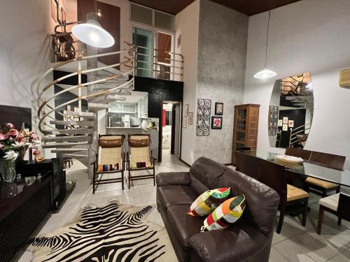 ein Wohnzimmer mit einem Ledersofa und einer Wendeltreppe in der Unterkunft Flat 414 Condominio Villa Hípica - Gravatá PE in Gravatá