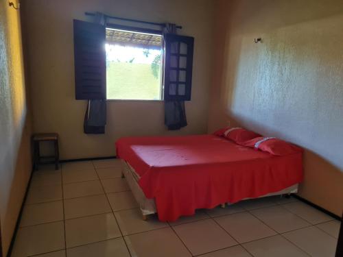een slaapkamer met een rood bed en een raam bij Casa Camboas in Paraipaba