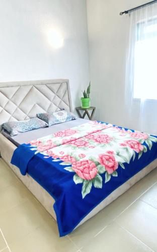 a bed with a blue and white comforter with flowers on it at Cozy Apartment in the City Centre - Rayfield Jos in Zawan