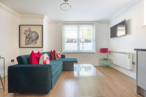 a living room with a blue couch and red pillows at Beaumont House in Royal Tunbridge Wells