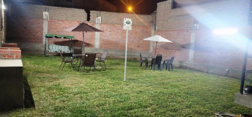 eine Gruppe von Stühlen und Tischen mit Sonnenschirmen in der Unterkunft Hostal Kmr in Lurigancho-Chosica