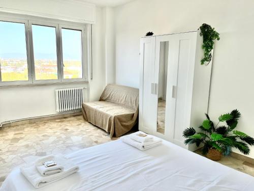 een witte slaapkamer met een bed en een bank bij Skyscraper 11 in Cinisello Balsamo