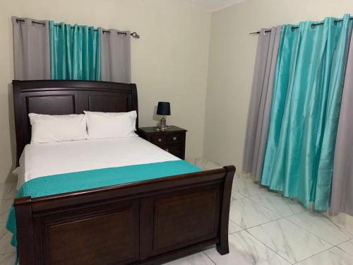 a bedroom with a bed and blue curtains at TOWNHOUSE GET-a-WAY in Mandeville