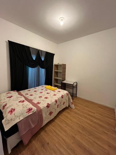 a bedroom with a bed with a floral comforter at Suíte Hostel Curitiba in Curitiba