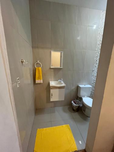 a small bathroom with a toilet and a yellow rug at Suíte Hostel Curitiba in Curitiba