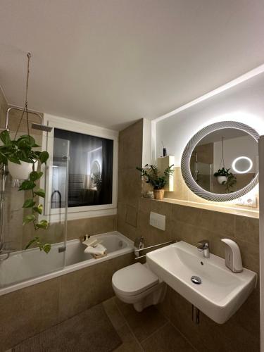 La salle de bains est pourvue d'un lavabo, de toilettes et d'une baignoire. dans l'établissement Hellenbrand: Stilvolles Apartment über den Dächern, à Kaiserslautern