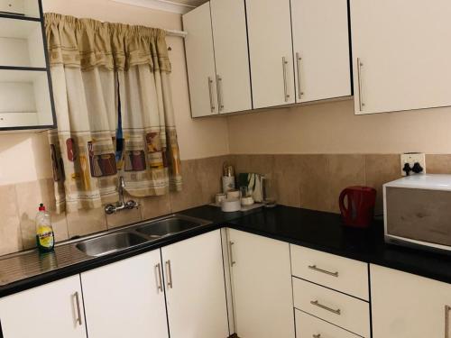 a kitchen with white cabinets and a sink at GoldenWays Apartment 3 in Mbabane