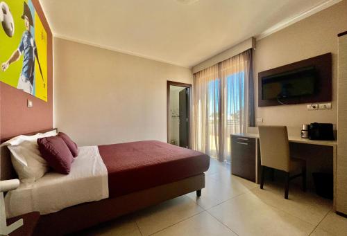 Habitación de hotel con cama, escritorio y TV. en Jogo Rooms en Matera